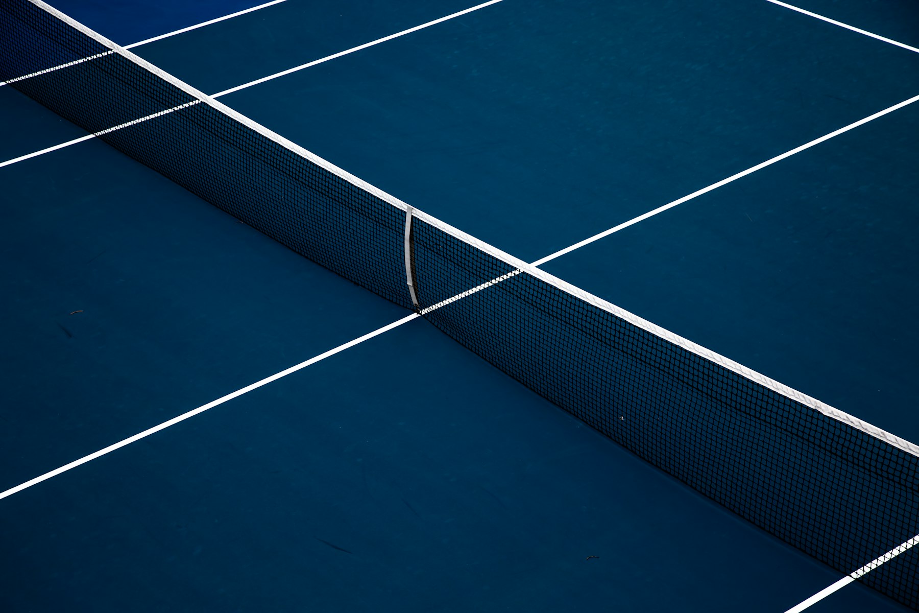 Freshly resurfaced blue acrylic tennis court with crisp white lines