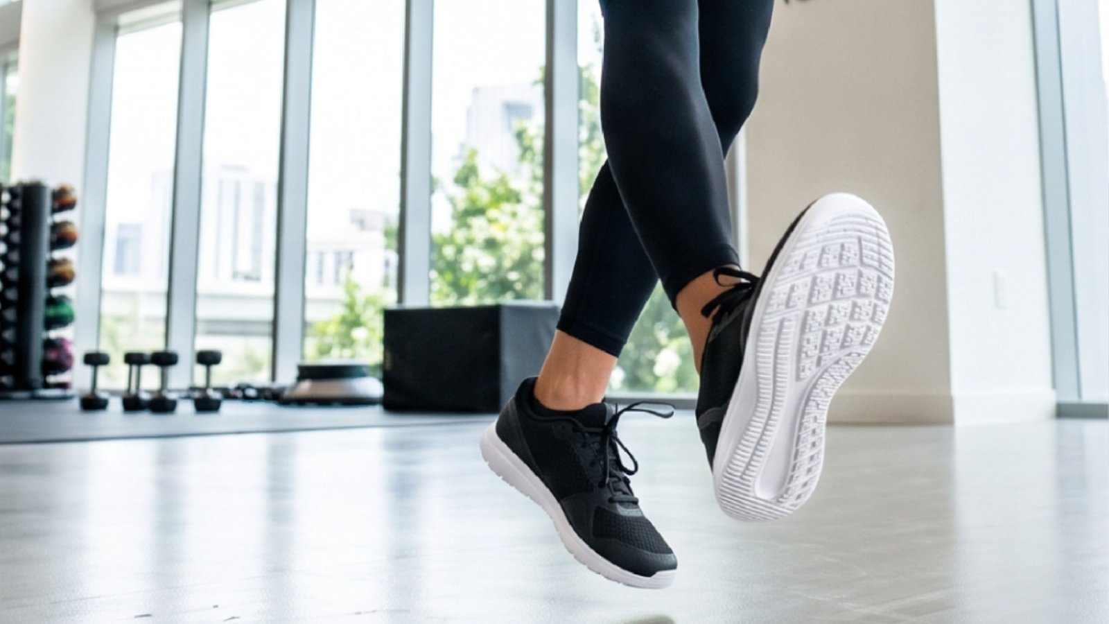Close-up of an athlete's legs and black training shoes mid-jump on an indoor gym floor, cropped from Dryello's official product images