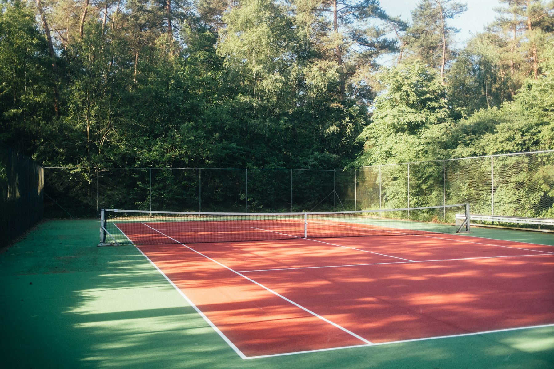 Outdoor tennis court surrounded by mature trees